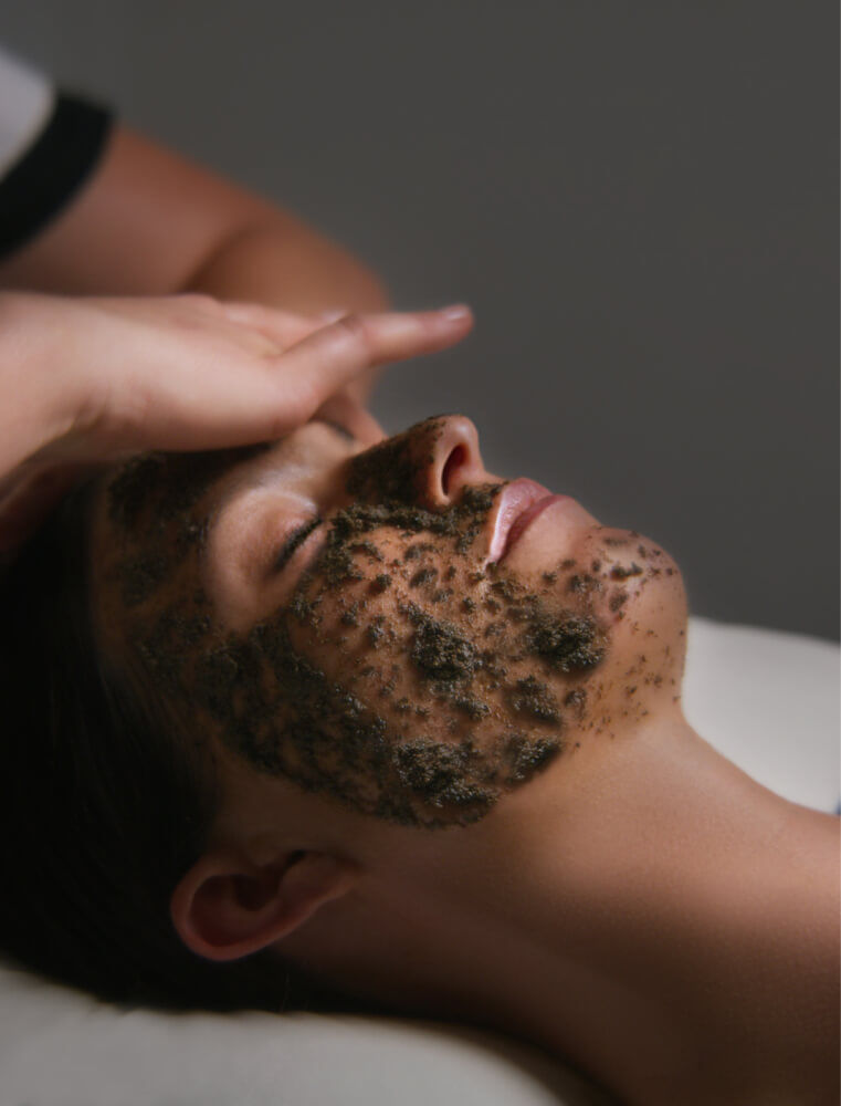  Facial treatment with a thick, textured exfoliating mask applied.
