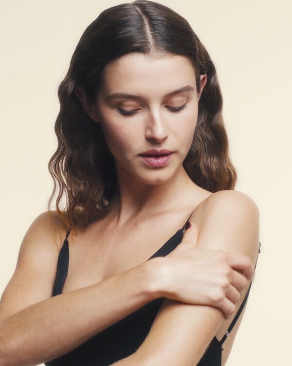 A woman’s hands massaging her shoulder with oil.