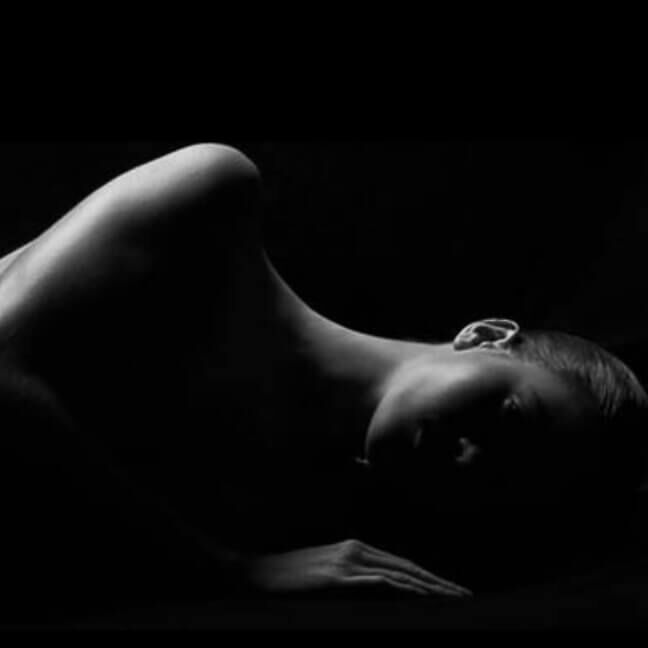 A silhouette of a reclining figure against a black background, highlighting the curves and smooth lines of the body.