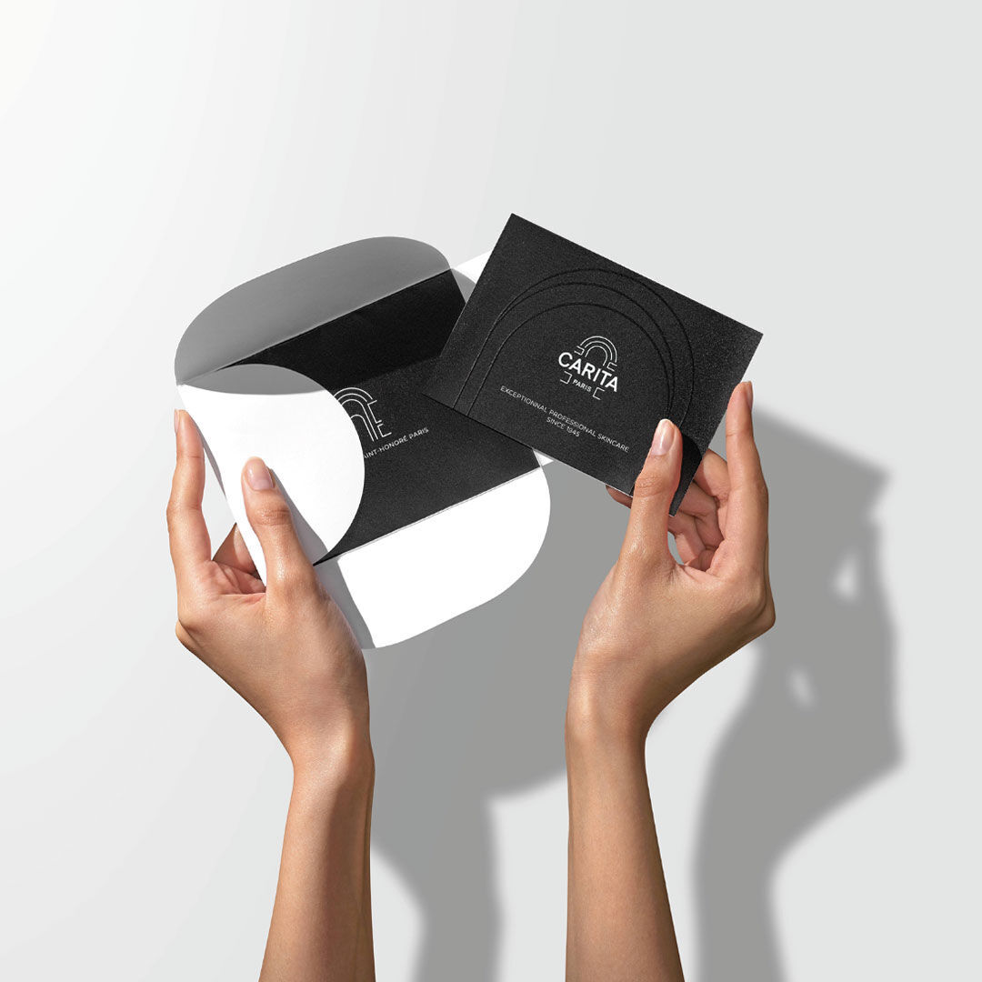 Hands opening a black pouch with a black gift card.