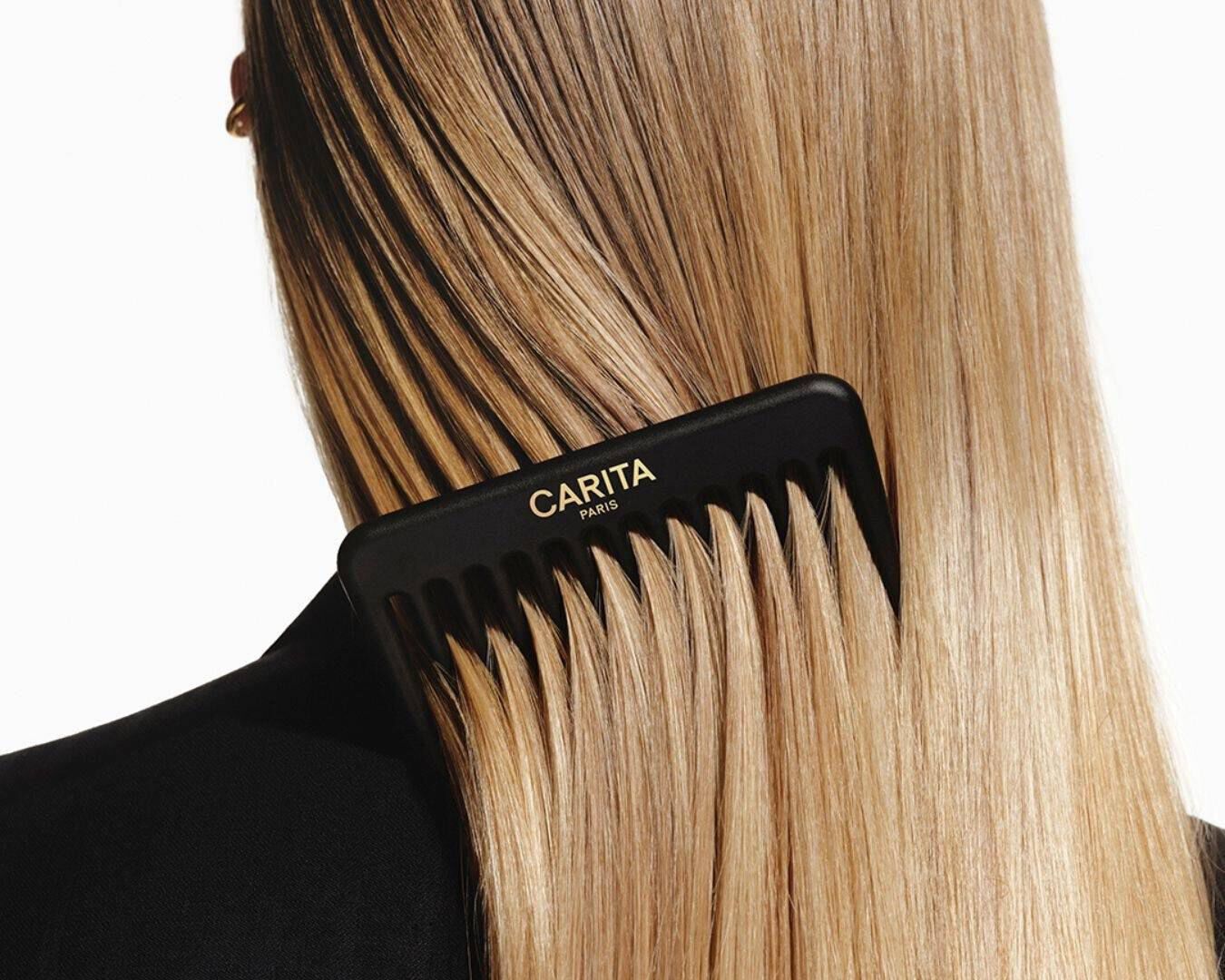 A black Carita comb detangling long, straight blonde hair.