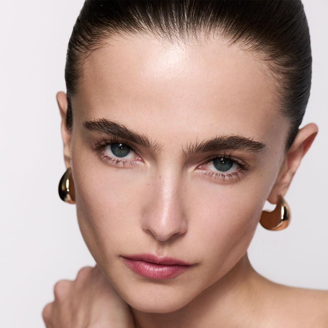 Brunette woman with sleek hair and gold earrings.