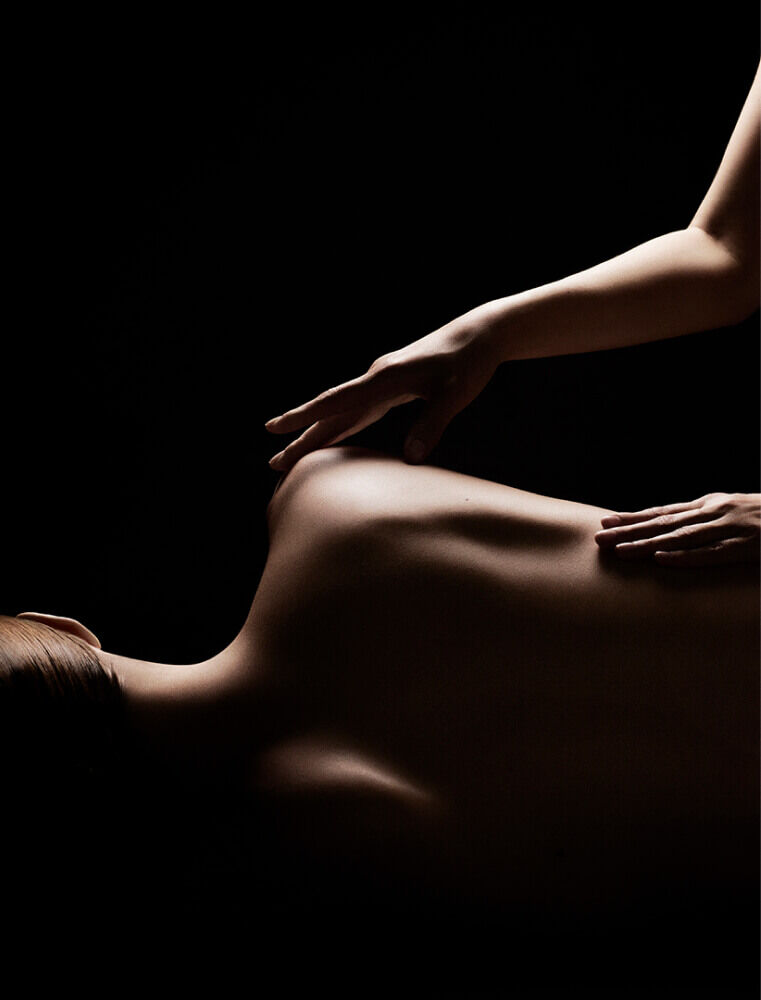Dramatic lighting of a professional back massage in a spa setting.