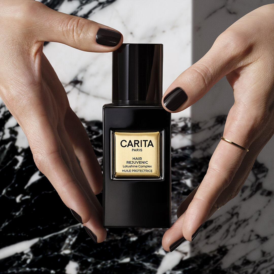 Hands holding the bottle of Carita’s Lumino-Protective Oil.