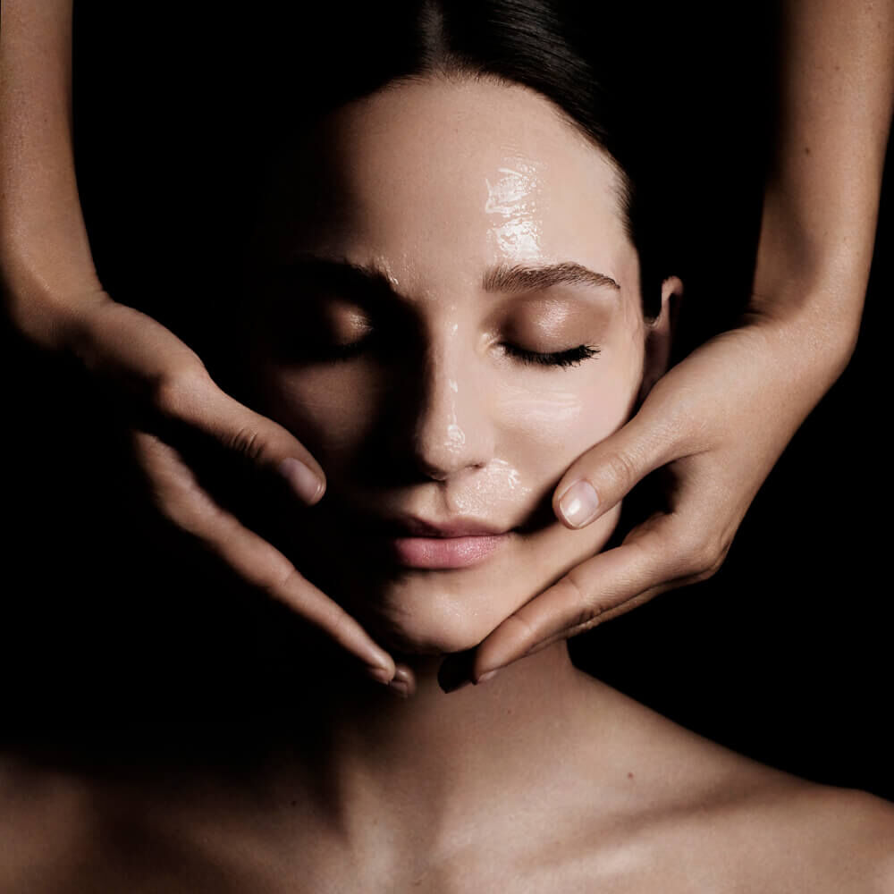 Hands framing a glowing face under dramatic lighting.