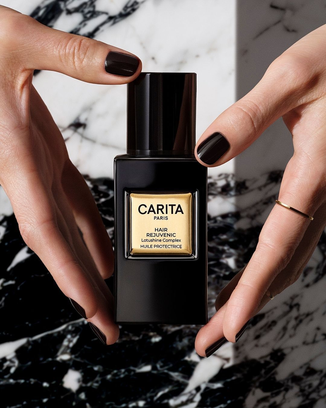 Hands holding the bottle of Carita’s Lumino-Protective Oil.