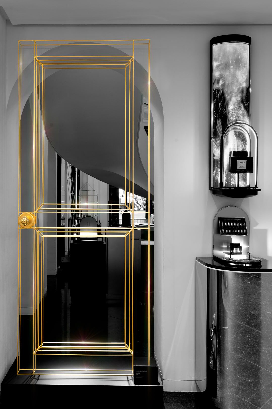 A stylish interior featuring a doorway outlined in golden lines, set against a monochrome background. The space includes elegant lighting and modern decor elements.