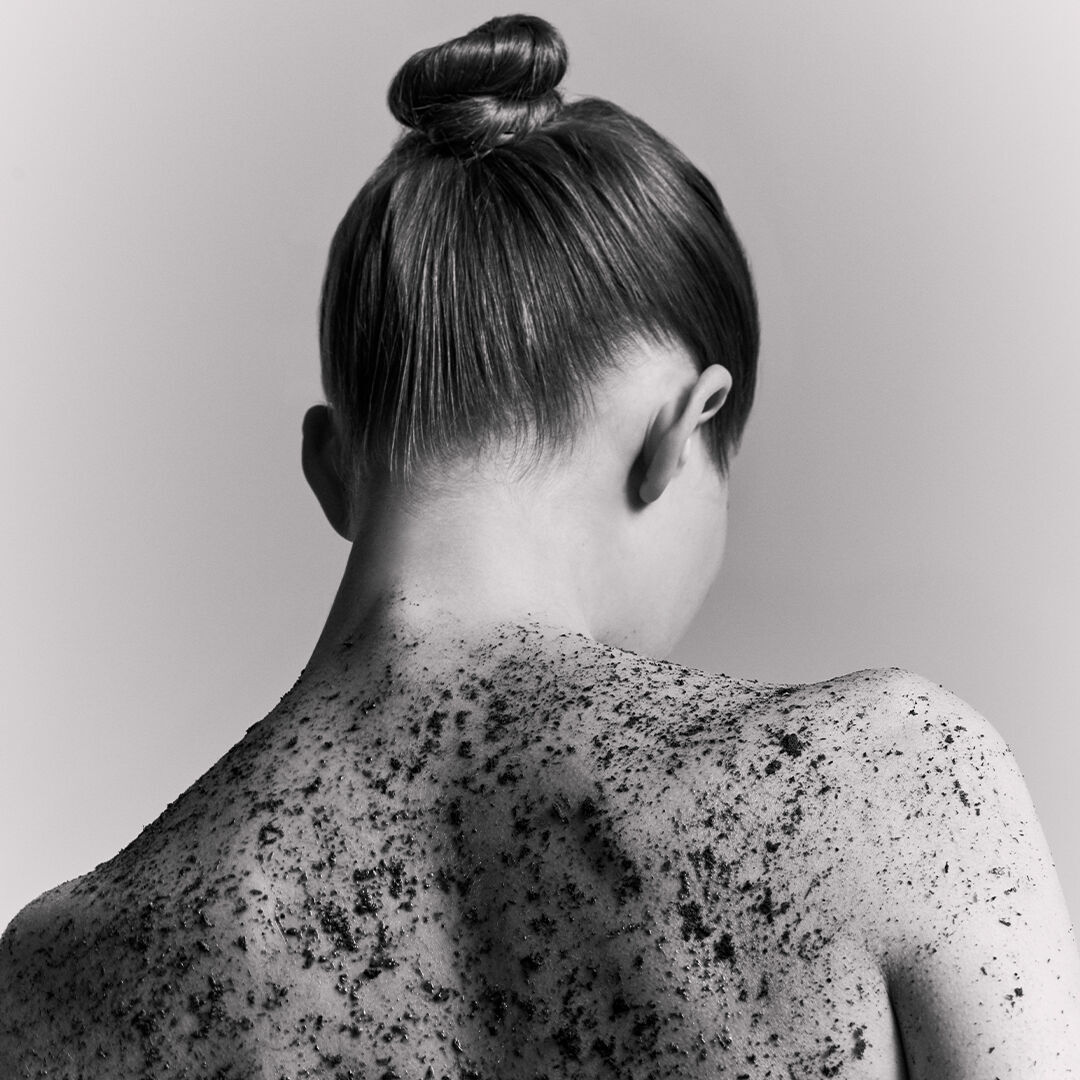 Back portrait of a woman with a textured body scrub.