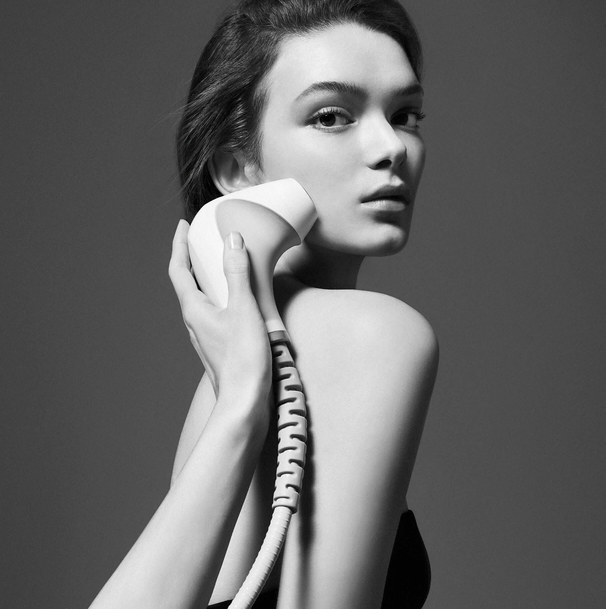 A black and white image of a woman holding a skincare product, with a jar and dropper bottle from the brand "CARTA" displayed on the right. The background is minimalistic and sleek.