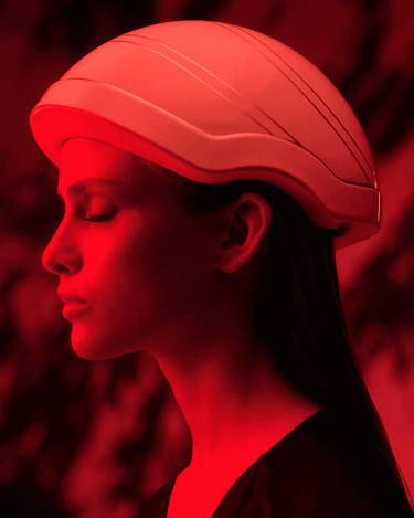 A woman wearing the red Hair OVE Light LED helmet under red lighting.
