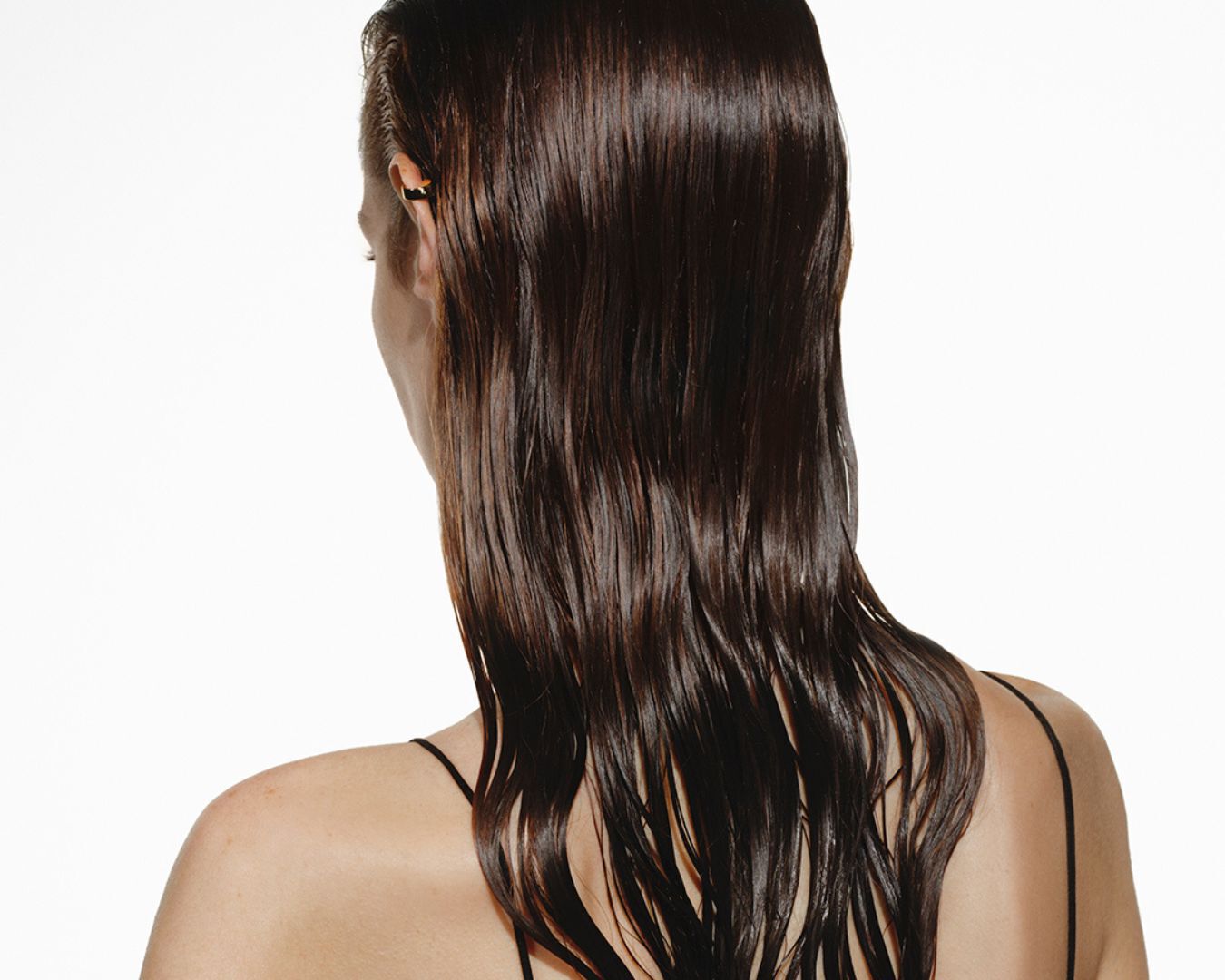The back of a woman with long, damp, wavy brown hair.