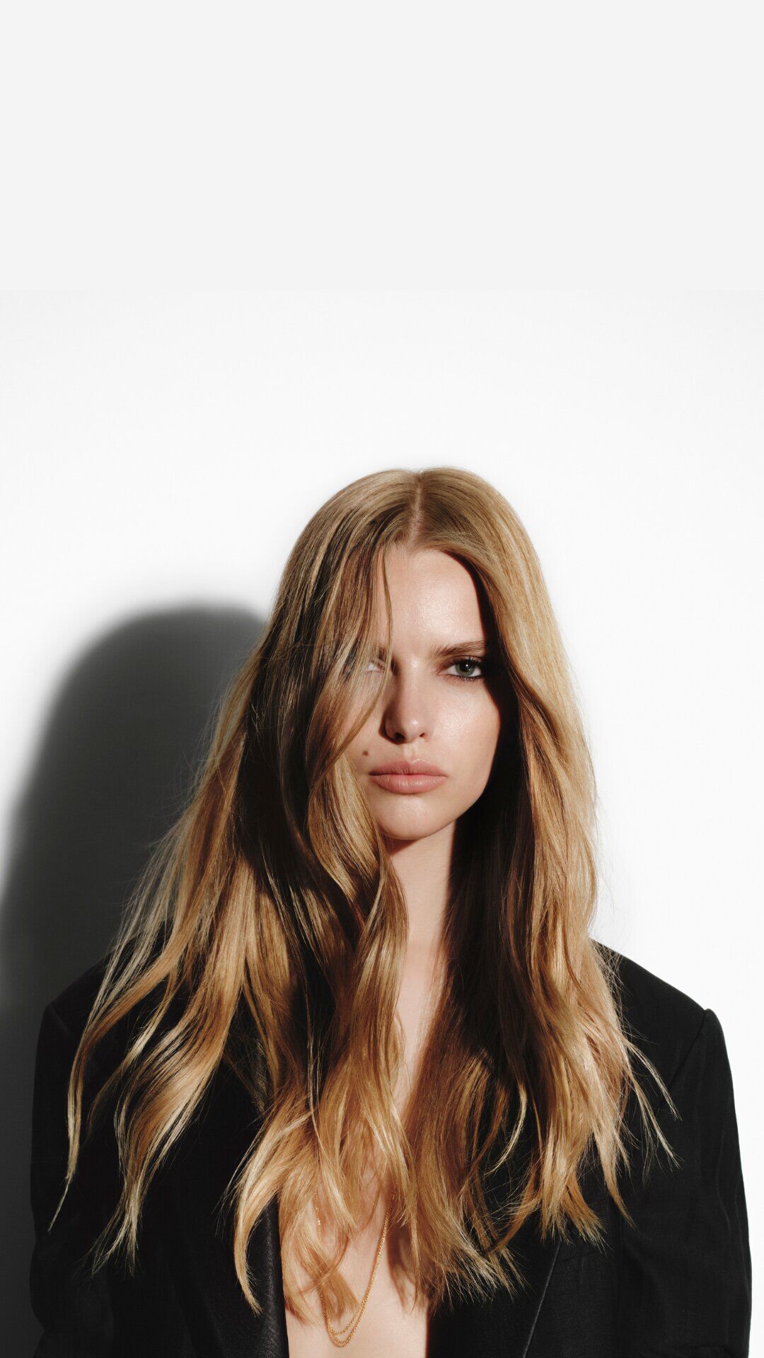 A blonde woman with long, wavy hair, wearing a black Carita jacket.