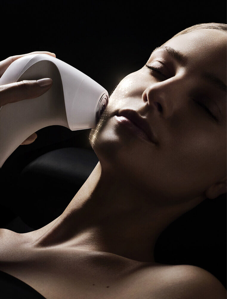 Professional using an electronic skin tightening device on face.