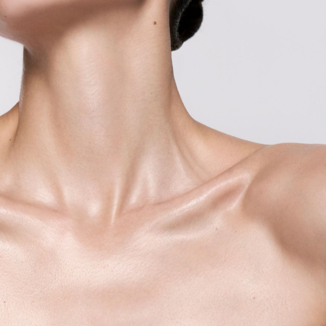A close-up of a woman’s bare, illuminated neck and collarbone.
