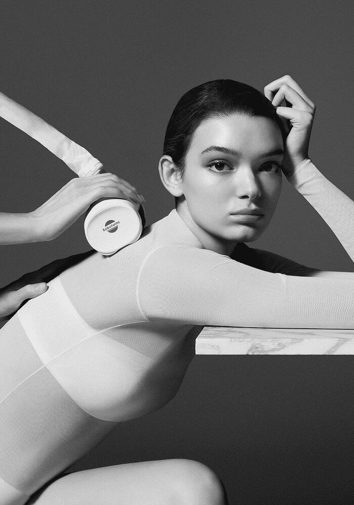 A black-and-white photograph showing a Carita treatment session using Icoone technology on the upper back of a young woman.