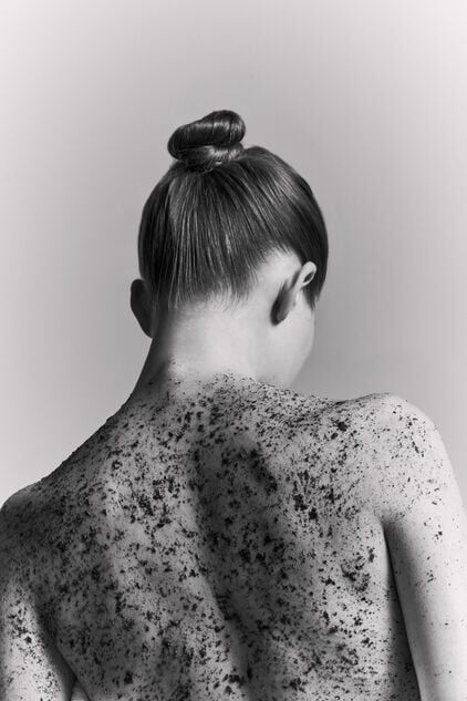 A portrait of a woman’s back featuring a textured body scrub.