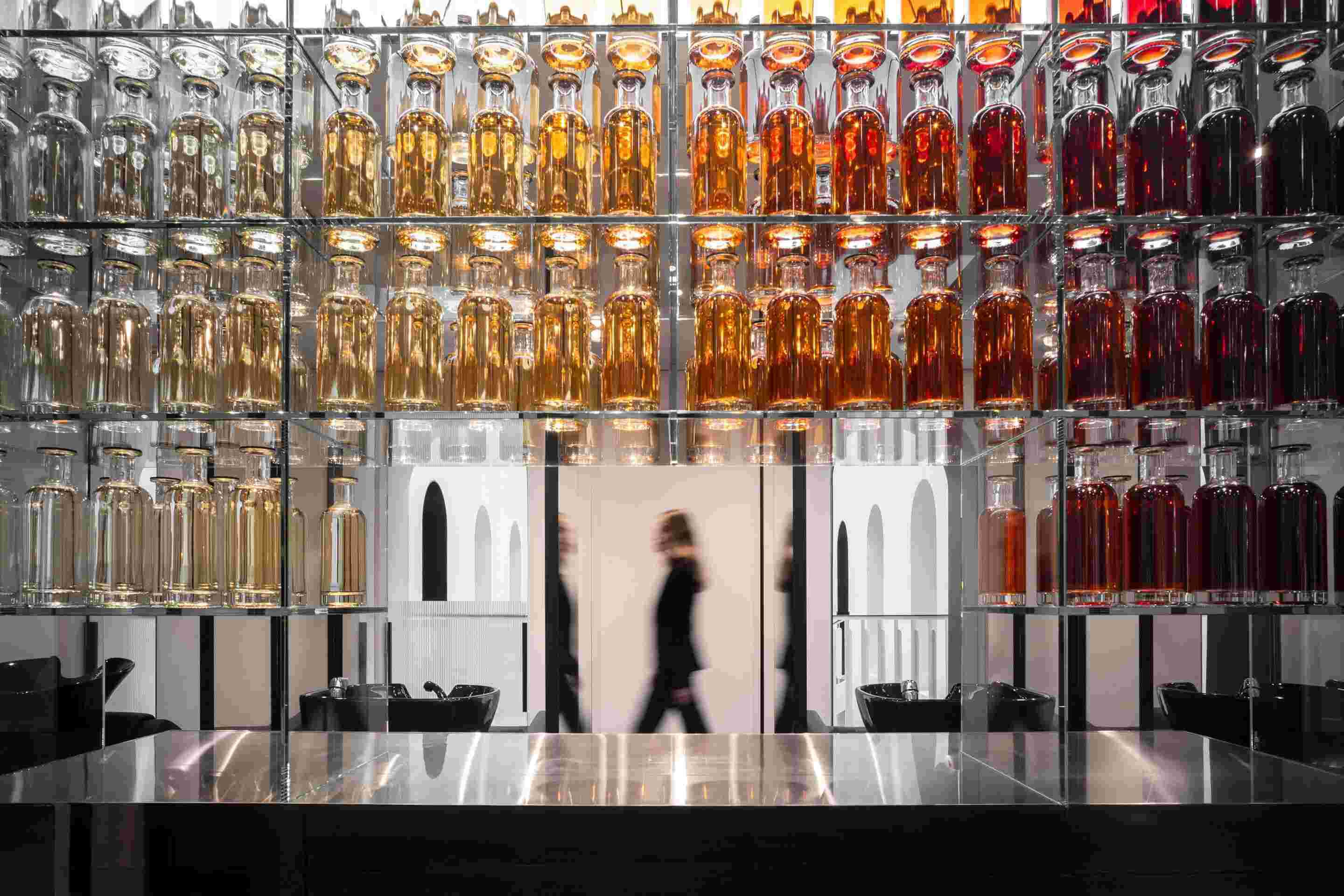 Bottles lined up and figures walking around the 11 Faubourg showroom.