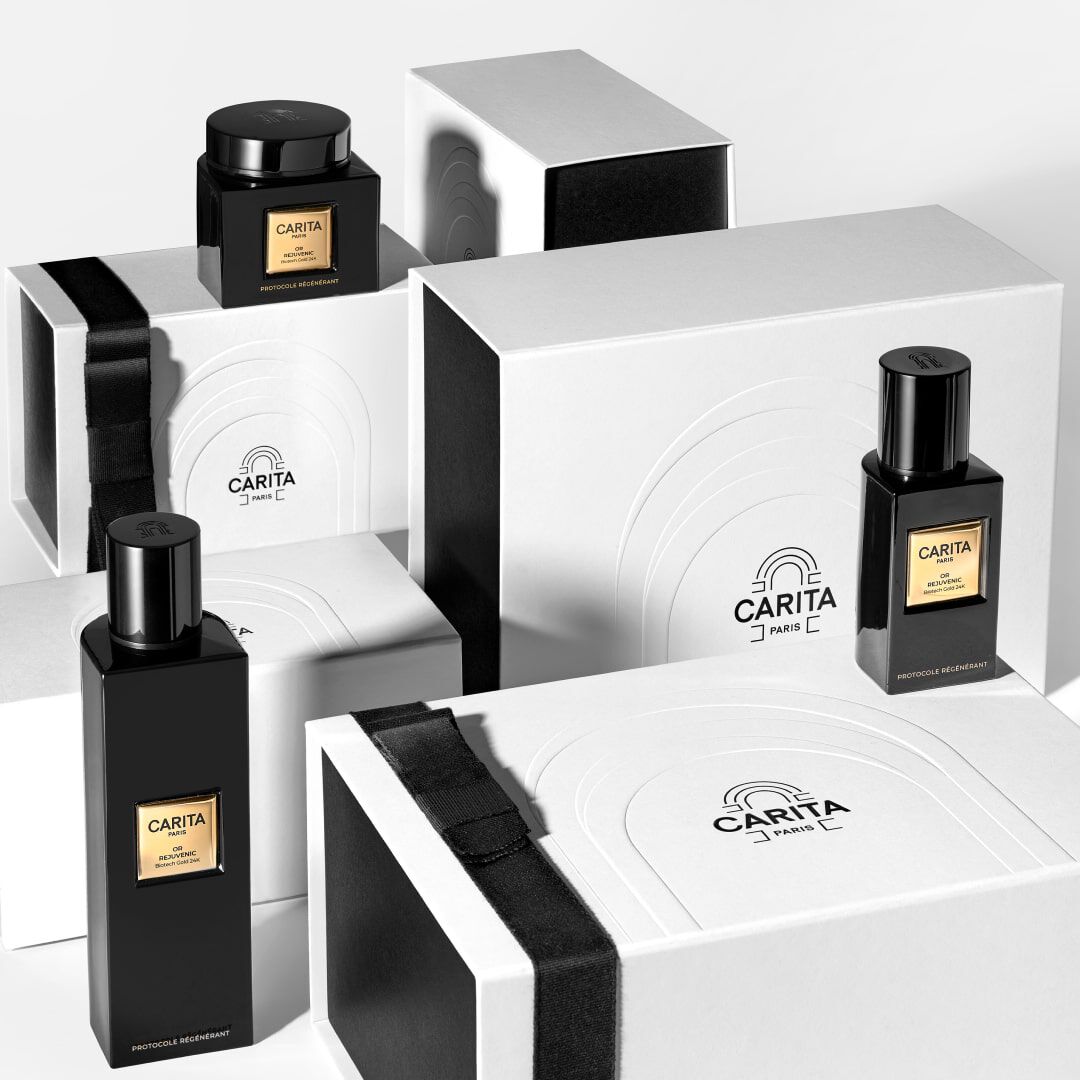 A collection of elegant black perfume bottles and stylish white boxes with black and gold accents, arranged in a modern display on a light background.