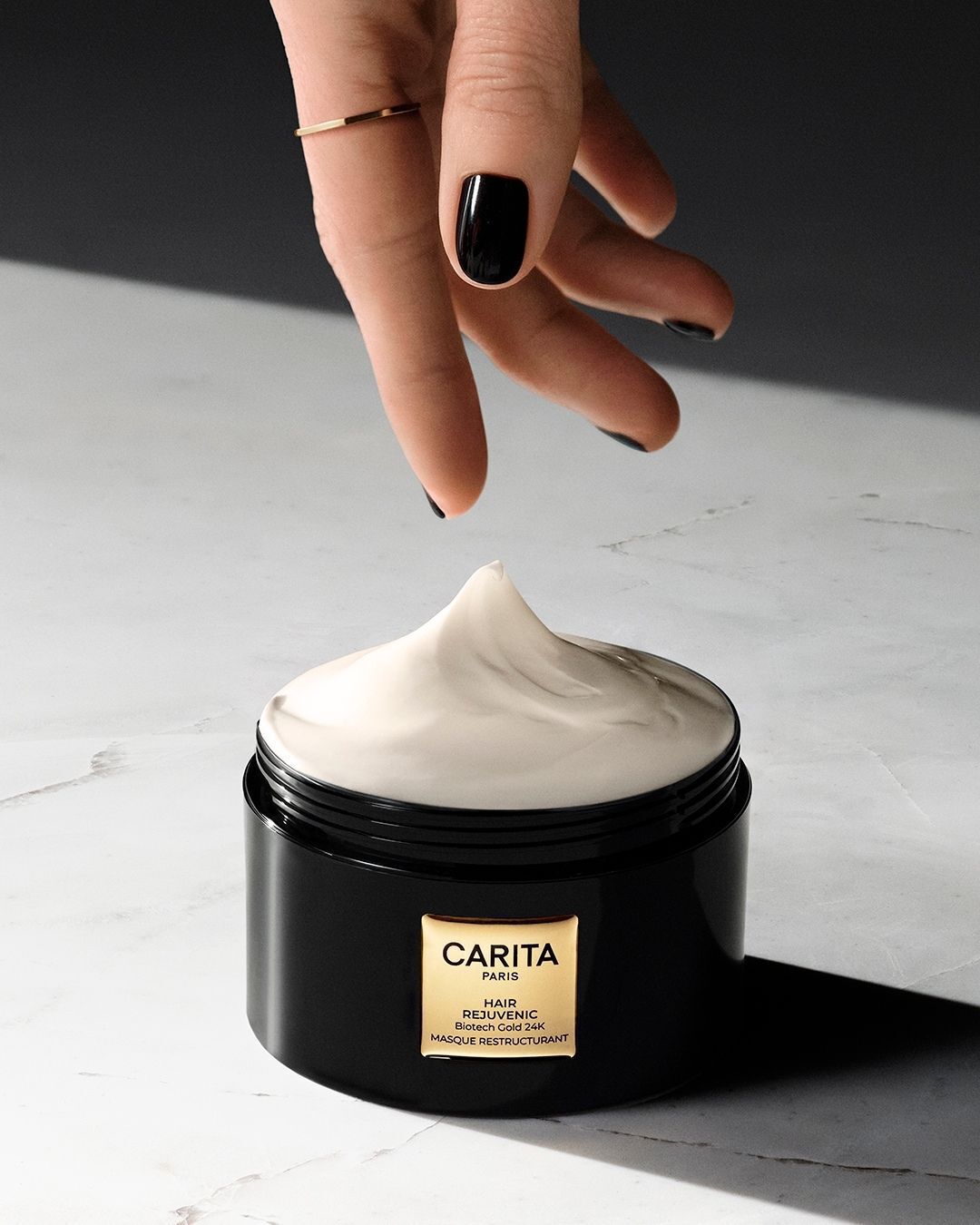 A hand scooping cream from the Hair Rejuvenic mask jar.