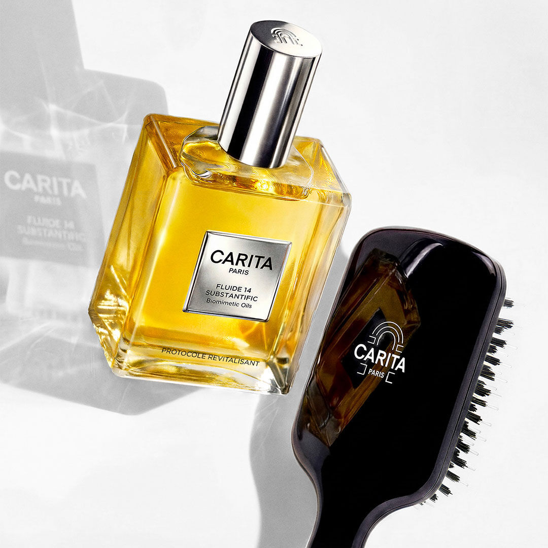 Golden Fluide 14 bottle next to a black hairbrush.