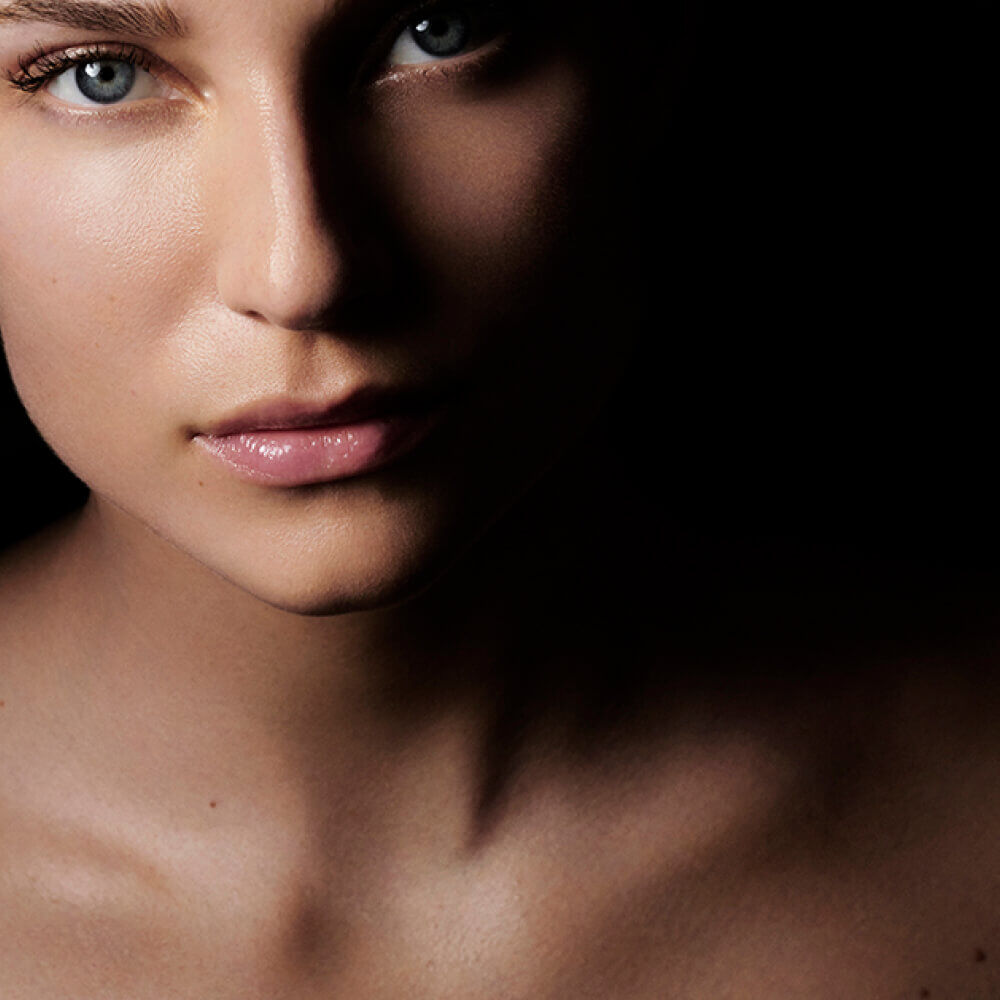 Dramatic close-up of a face emerging from deep shadows.