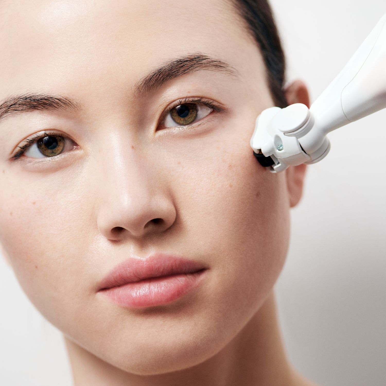 Luminous skin perfected by an advanced beauty device. A luxurious treatment for a radiant complexion, on a pristine backdrop.