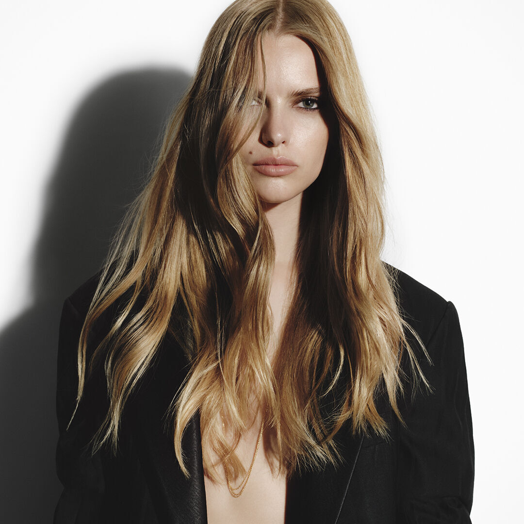 Blonde woman with long wavy hair in a black Carita jacket.