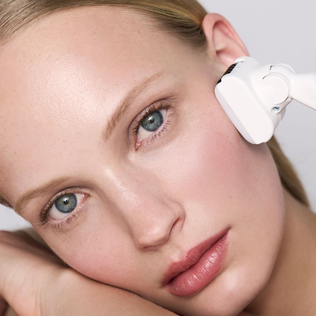 A woman having a facial treatment using a white beauty device.