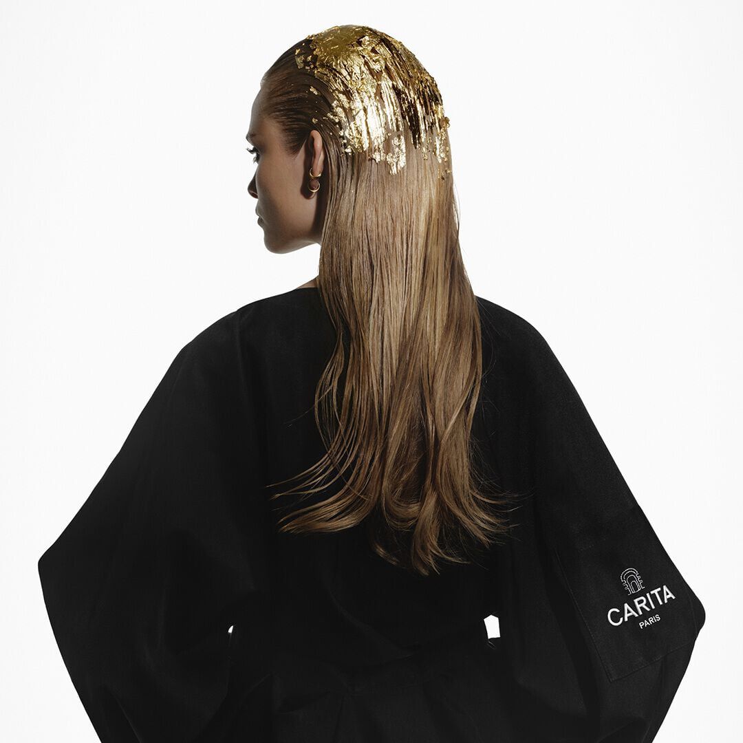 Blonde woman with gold leaf hair in a black Carita robe.