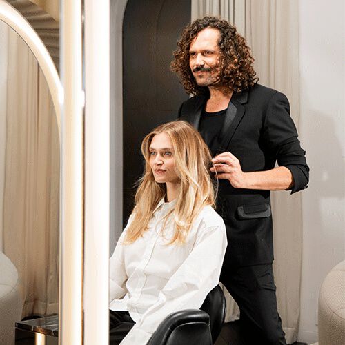 A woman dressed in a white shirt sits on a couch, exuding a sense of comfort and tranquility.